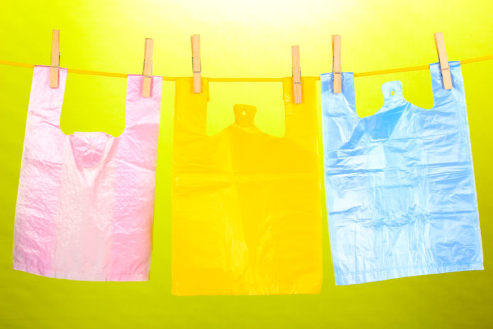 Cellophane bags hanging on rope on green background